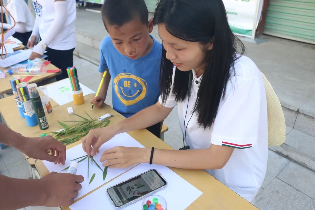 圖為實踐隊員和當地留守兒童使用掉落的樹葉創作樹葉字。胡馨文 供