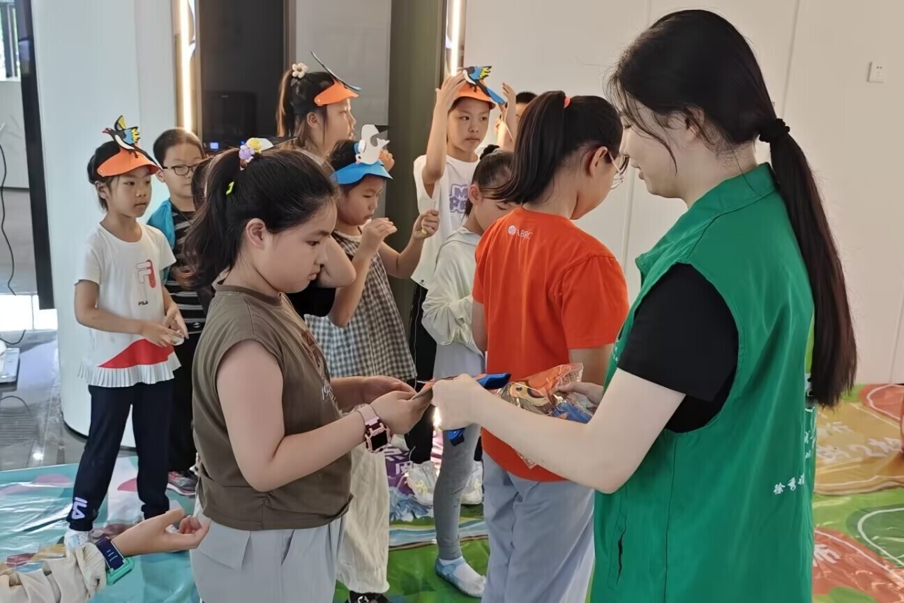 图为实践团成员在给孩子们分发自然探索创意DIY的手工材料与趣味儿童头饰。于维豪 供图