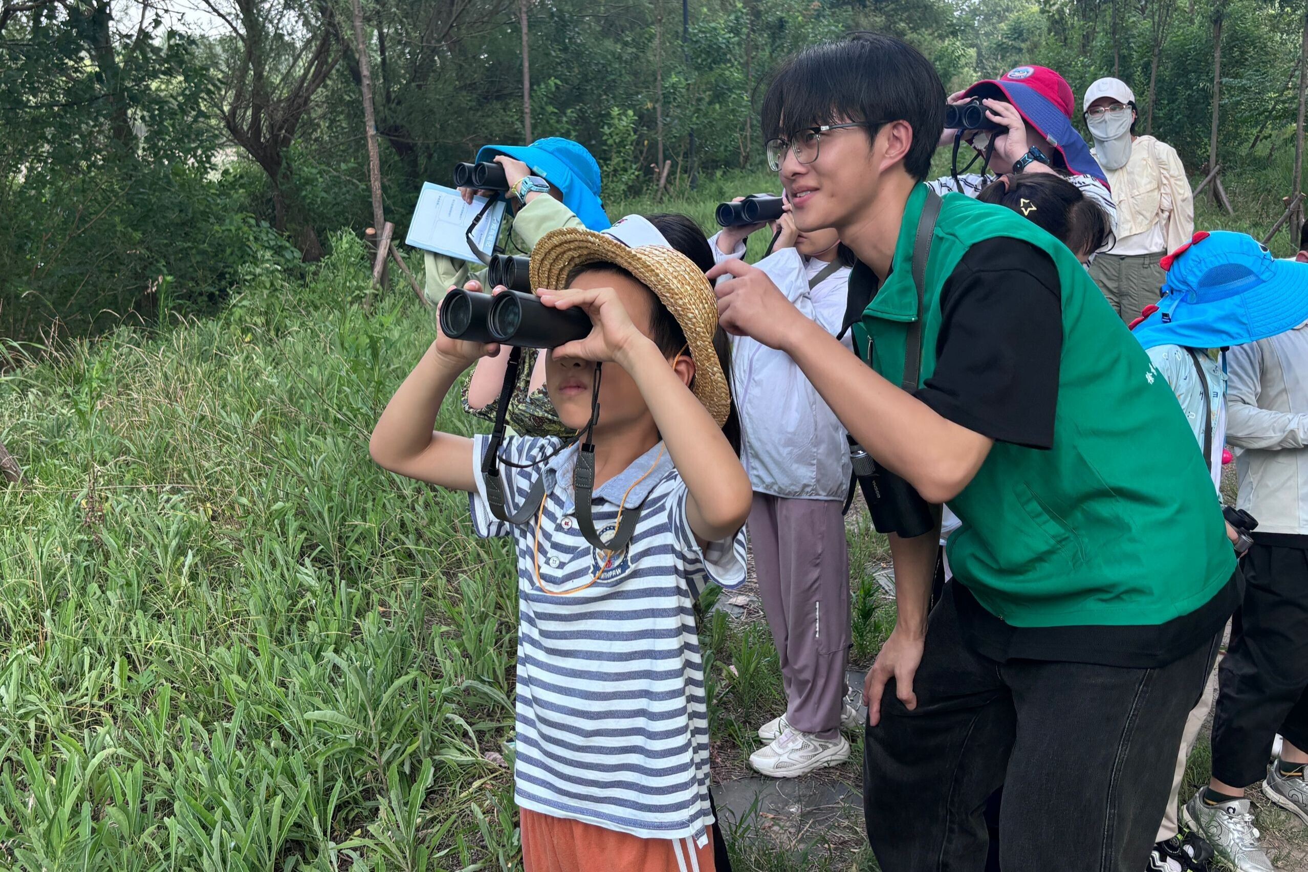 图为实践团志愿者一对一指导孩子认识使用望远镜，指导观察鸟类。朱钦迟 供图