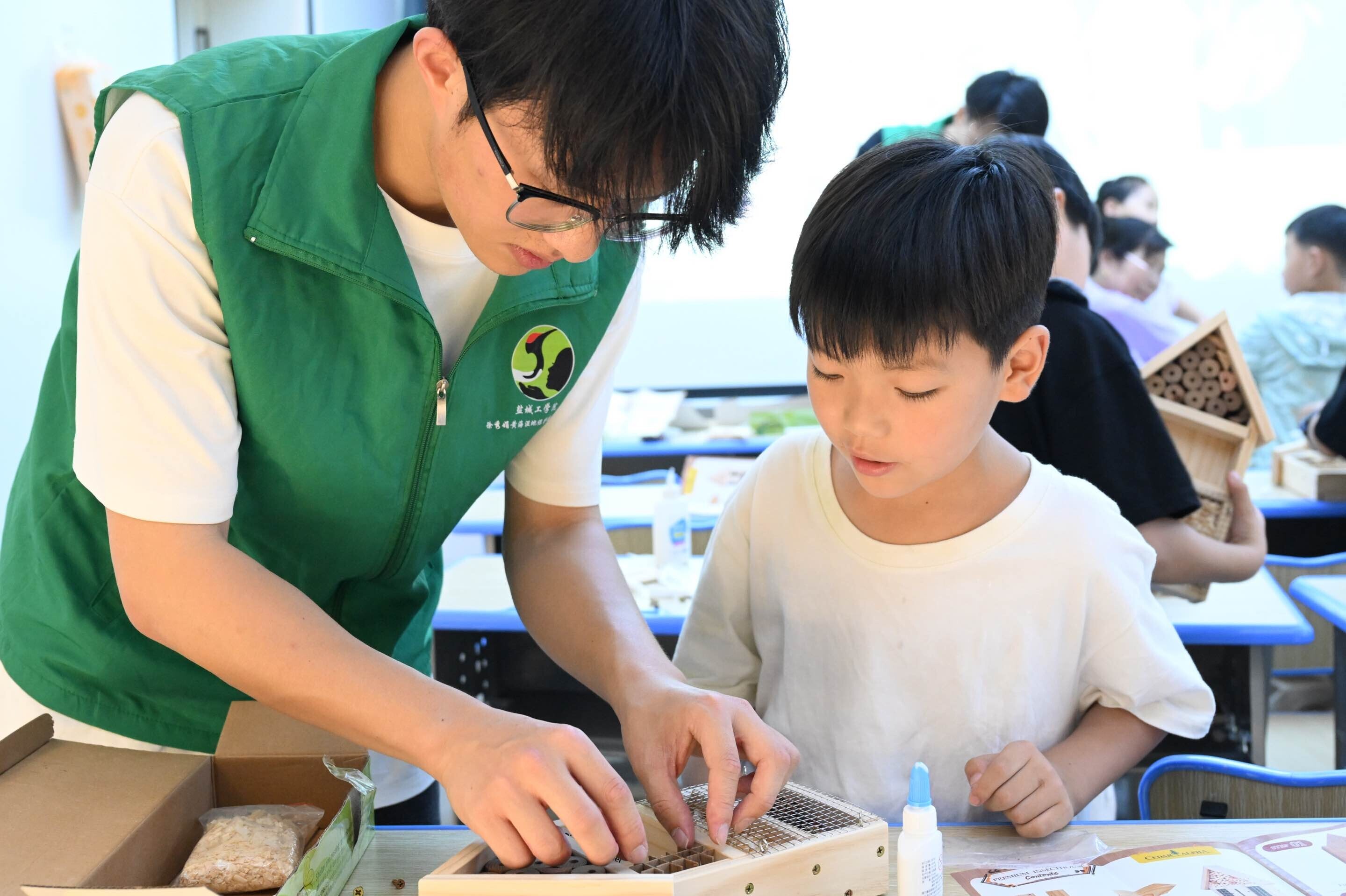 图为实践团成员帮助小朋友们组装 “昆虫旅馆”模型。黄淼 供图