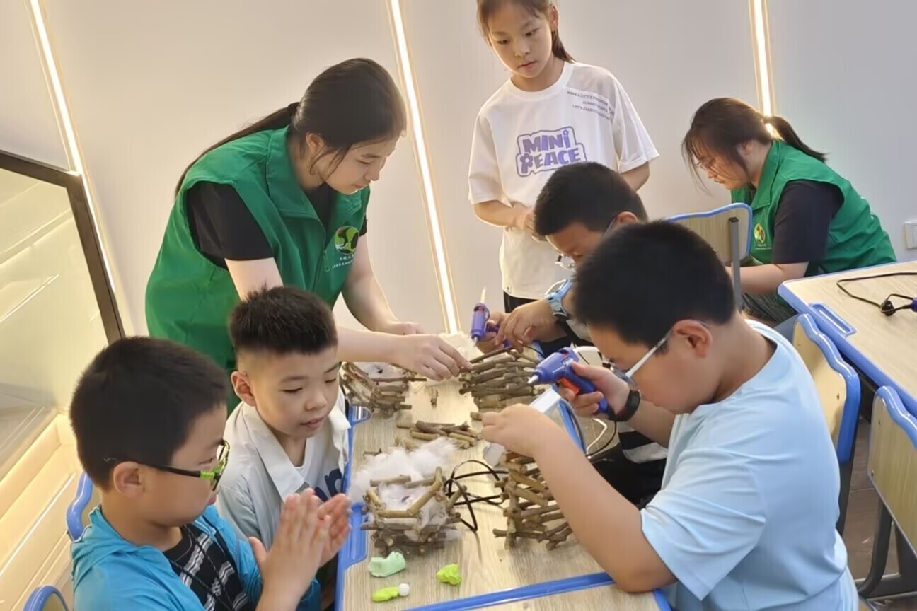 图为实践团成员与孩子们巧用树枝、棉花模拟讲解鸟类筑巢过程。于维豪 供图