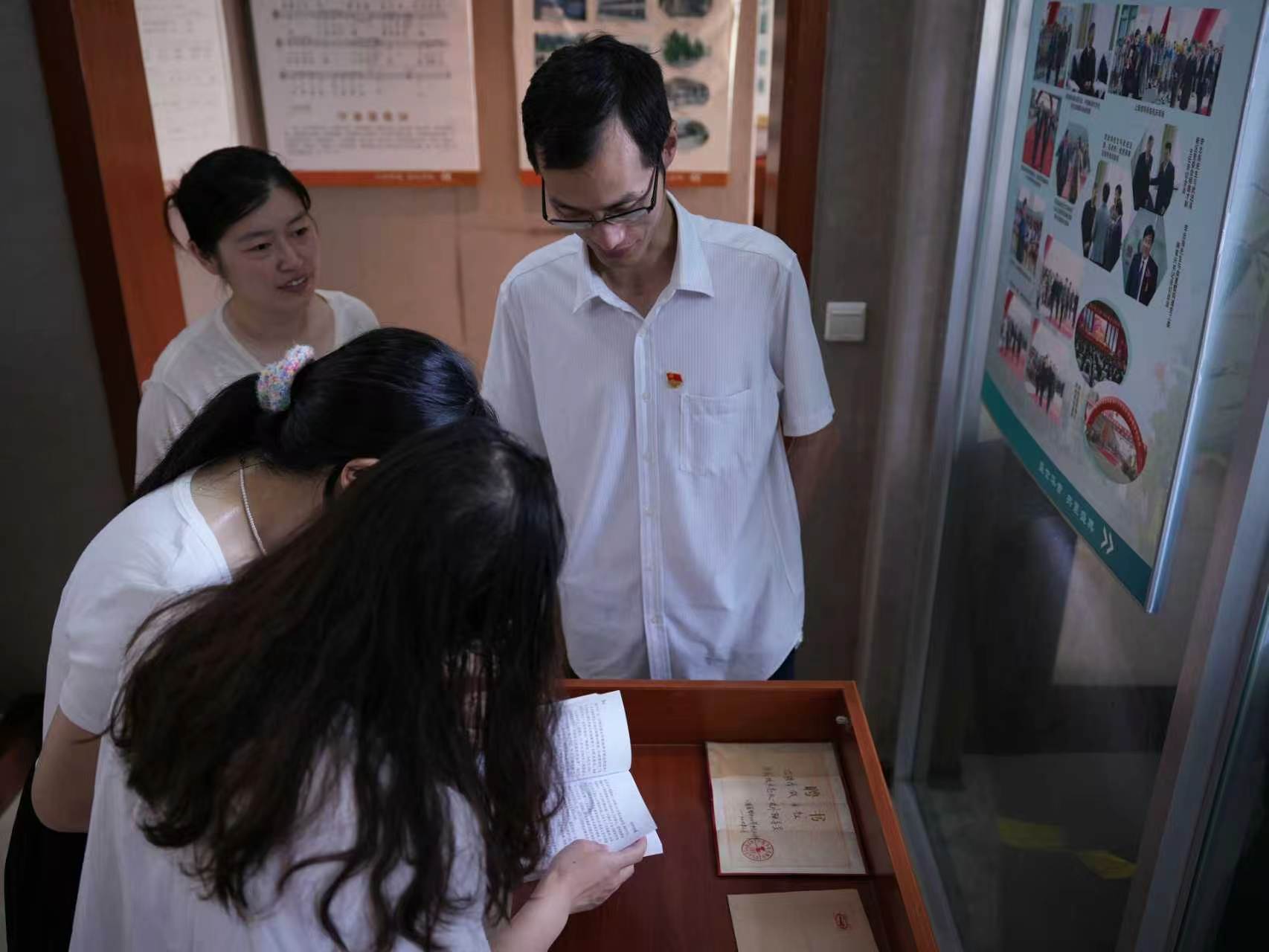 员工在南夏墅中心小学校史馆翻阅校本教材